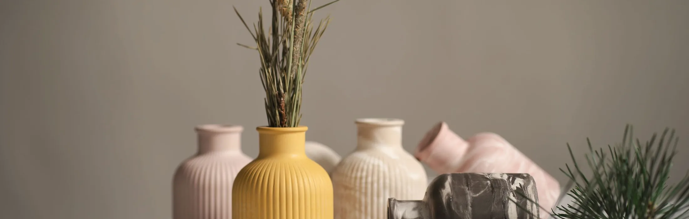 Hand-thrown ceramic vases and dried grasses on a plaster shelf